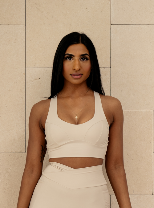 Corset Crop in Oatmilk, a cream sports bra with contour seams, front view on a model